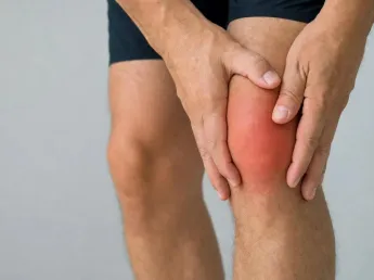 What is gout? A man holding a red, swollen knee joint inflamed by gout