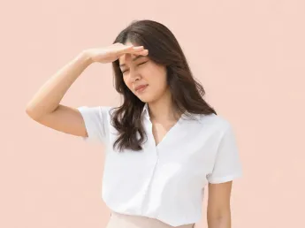 Migraine symptoms — woman shielding her eyes from light sensitivity